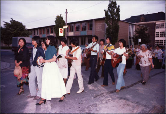 Men and women playing instruments and singing in a Filipino Santacruza religious procession