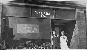 Exterior view of a Finnish Cooperative Merchants Ltd. store with the manager and clerk standing in front